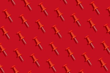 Kırmızı arka planda kırmızı kırtasiye iğneleri deseni. Okul konseptine geri dön, üst görünüm