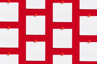 Kırmızı zemin üzerine raptiye iliştirilmiş notlar için boş beyaz kağıt levha deseni. Kırmızı arka planda ofis ve okul malzemeleri. Okul konseptine geri dön, üst görünüm