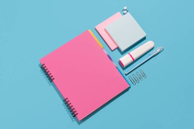 Not defteri, fosforlu kalem, raptiye ve kağıt kağıtlar mavi arka planda. Ofis ve okul malzemeleri mavi arka planda. Okul konseptine geri dön, üst görünüm