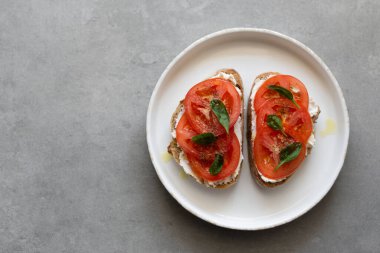 Krem peynirli kahvaltı tostları, taze domates, zeytinyağı ve beyaz tabakta bebek ıspanağı. Sağlıklı lezzetli yiyecek konsepti, üst görünüm, kopyalama alanı