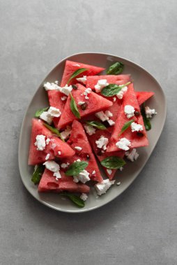 Feta peynirli taze karpuz, bebek ıspanak ve taş zeminde limon suyu. Sağlıklı ve estetik yaz tatlısı, karpuz tarifi. Üst görünüm, alanı kopyala