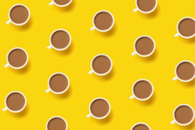 Sarı arka planda kahve fincanlarıyla yapılmış bir kalıp. Yaratıcı kahvaltı konsepti, üst görünüm