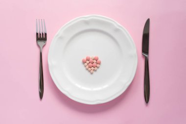 Pembe arka planda beyaz bir tabletteki pembe yuvarlak tabletlerin üst görüntüsü. Yaratıcı haplar konsepti, kopyalama alanı