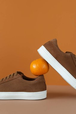 Kahverengi erkek minimalist botlarının bej ve turuncu arka planda turuncu çizmeleri. Sonbahar konsepti, sonbahar renkleri