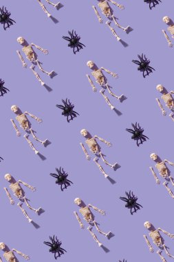 Cadılar Bayramı örümcekleri ve pastel mor arka planda kırık plastik iskelet deseni. Yaratıcı Cadılar Bayramı konsepti, üst görünüm, kopyalama alanı