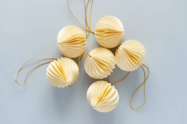 Açık mavi arka planda bir Noel ağacını süslemek için bej kağıt süsler. Kutlama havası ve dekorasyon Noel ağacı konsepti, üst görünüm, kopyalama alanı