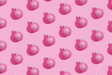 Pastel pembe arka planda parıldayan Noel toplarının yaratıcı deseni. Yaratıcı Noel pembe arka planı, üst görünüm