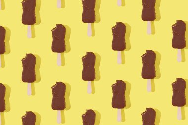 Sarı arka plandaki çubukta çikolatalı dondurma deseni. Asgari yiyecek fotoğraf konsepti, üst görünüm