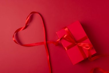 Noel temalı Xmas hediye kutusu ve dekorasyon kutlaması. Kırmızı arka planda kırmızı mevcut kutu. Kırmızı kurdeleli Sevgililer Günü hediyesi kutusu. Monokrom renk şeması, üst görünüm, boşluk kopyala