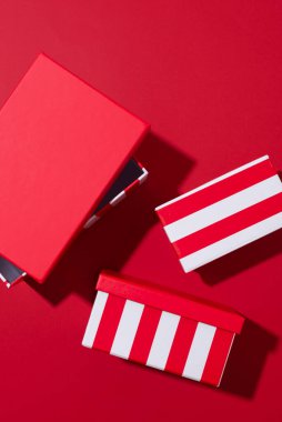 Kırmızı zemin üzerinde beyaz çizgili üç kırmızı set Noel hediyesi kutuları farklı boyutlarda. Asgari Noel ya da yeni yıl hediyeleri konsepti. Monokrom renk şeması, üst görünüm, boşluk kopyala