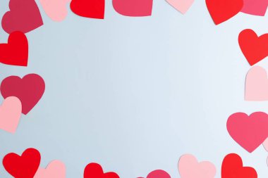 Pastel mavi arka planda çeşitli boyutlarda kırmızı ve pembe kağıt kalpler var. Sevgililer Günü, aşk ve duygular konsepti, üst görünüm