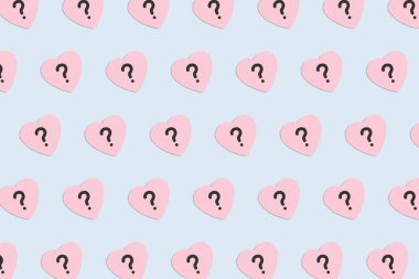 Pastel mavi arka planda soru işareti olan pembe kağıt kalp deseni. Sevgililer Günü, aşk ve duygular konsepti, üst görünüm