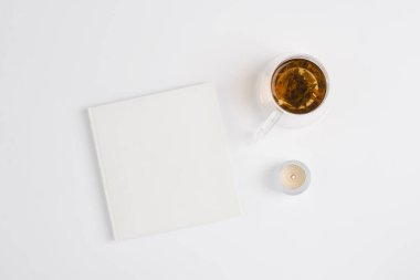 Beyaz arka planda çay fincanı olan beyaz bir defter. Yeni yıl için hedefler ve planlar kavramı. Farkındalık kavramı, üst görünüm, kopyalama alanı