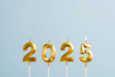 Pastel mavi arka planda 2025 'i oluşturan sayılı şenlikli altın mumlar. Altın numara doğum günü veya yeni yıl mumları, kopyalama alanı
