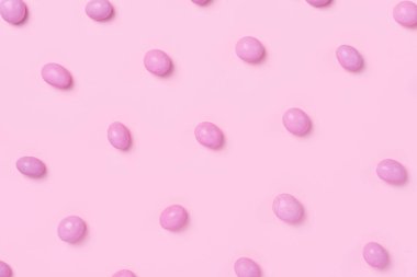 Pembe arka planda pembe bir paskalya elbisesi. Pembe jöleli yumurta şeklinde tatlı şekerler. Yaratıcı paskalya konsepti, üst görünüm