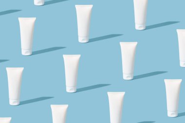 Kozmetik beyaz tüplerin modelleri. Boş, mavi arkaplanda krem ya da jöle paketlemek için kozmetik tüpler deseni oluşturur.