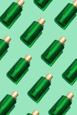 Yeşil bir arka planda duran yeşil parfüm şişesinin deseni uzun bir gölge ve güzel bir ışık yansıması. Modern lüks parfüm şişesi, tazelik konsepti, üst manzara.