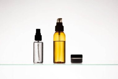 Beyaz arka planda cam bir rafta farklı kozmetik ürünler. Cam bir rafta cilt bakımı ve banyo ürünleri. Güzellik ürünleriyle dağıtıcılar ve tüpler.