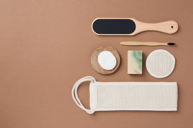 Kahverengi arka planda banyo aletleri ve organik kozmetik ürünlerinin üst görünümü doğal, çevre dostu güzellik gereksinimlerini ve kişisel bakım rutin konseptini vurguluyor. Doğal cilt bakımı ve sağlıklı yaşam ürünleri. 