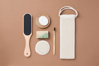 Kahverengi arka planda banyo aletleri ve organik kozmetik ürünlerinin üst görünümü doğal, çevre dostu güzellik gereksinimlerini ve kişisel bakım rutin konseptini vurguluyor. Doğal cilt bakımı ve sağlıklı yaşam ürünleri. 