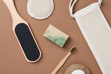 Kahverengi arka planda banyo aletleri ve organik kozmetik ürünlerinin üst görünümü doğal, çevre dostu güzellik gereksinimlerini ve kişisel bakım rutin konseptini vurguluyor. Doğal cilt bakımı ve sağlıklı yaşam ürünleri.