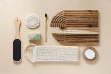 Banyo aletlerinin ve bej arka plandaki organik kozmetik ürünlerin üst görüntüsü doğal, çevre dostu güzellik gereksinimlerini ve kişisel bakım rutin konseptini vurguluyor. Doğal cilt bakımı ve sağlıklı yaşam ürünleri.