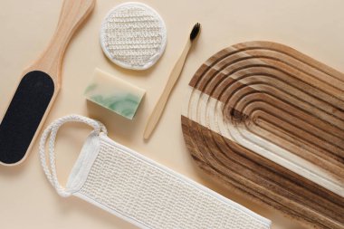 Banyo aletlerinin ve bej arka plandaki organik kozmetik ürünlerin üst görüntüsü doğal, çevre dostu güzellik gereksinimlerini ve kişisel bakım rutin konseptini vurguluyor. Doğal cilt bakımı ve sağlıklı yaşam ürünleri.