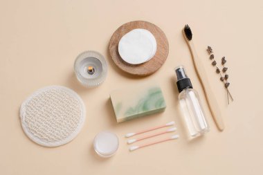 Banyo aletlerinin ve bej arka plandaki organik kozmetik ürünlerin üst görüntüsü doğal, çevre dostu güzellik gereksinimlerini ve kişisel bakım rutin konseptini vurguluyor. Doğal cilt bakımı ve sağlıklı yaşam ürünleri.