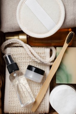 Banyo aletlerinin ve organik kozmetik ürünlerinin kahverengi arka planda doğal, çevre dostu güzellik gereksinimlerini ve kişisel bakım rutin konseptini vurgulayan dokuma sepetindeki üst görünümü. Doğal cilt bakımı ve sağlıklı yaşam ürünleri.