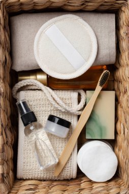 Banyo aletlerinin ve organik kozmetik ürünlerinin kahverengi arka planda doğal, çevre dostu güzellik gereksinimlerini ve kişisel bakım rutin konseptini vurgulayan dokuma sepetindeki üst görünümü. Doğal cilt bakımı ve sağlıklı yaşam ürünleri.