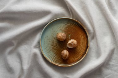 Yuvarlak plaka, bej rengi pamuk masa örtüsünün üzerinde sıcak renklerde bir kenarı var. Yumuşak renk paletinde doğal elementlerle minimalist kompozisyon. El yapımı ahenk konsepti, üst görünüm