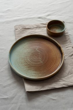 Yuvarlak plaka, bej rengi pamuk masa örtüsünün üzerinde sıcak renklerde bir kenarı var. Yumuşak renk paletinde doğal elementlerle minimalist kompozisyon. El yapımı ahenk konsepti, üst görünüm