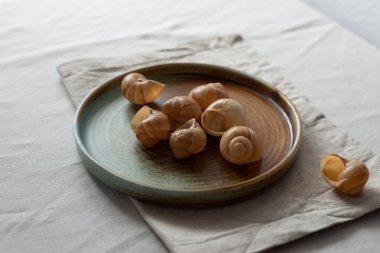 Yuvarlak plaka, bej rengi pamuk masa örtüsünün üzerinde sıcak renklerde bir kenarı var. Yumuşak renk paletinde doğal elementlerle minimalist kompozisyon. El yapımı ahenk konsepti, üst görünüm