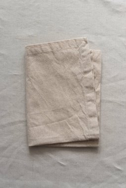 Bej rengi pamuk bir masa örtüsü üzerinde sıcak renklerde kumaş peçeteler. Yumuşak renk paletinde doğal elementlerle minimalist kompozisyon. El yapımı ahenk konsepti, üst görünüm 