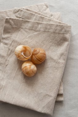 Bej rengi pamuk bir masa örtüsü üzerinde sıcak renklerde kumaş peçeteler. Yumuşak renk paletinde doğal elementlerle minimalist kompozisyon. El yapımı ahenk konsepti, üst görünüm