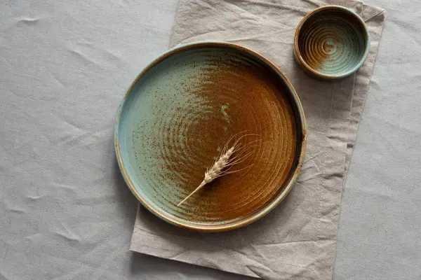 Yuvarlak plaka, bej rengi pamuk masa örtüsünün üzerinde sıcak renklerde bir kenarı var. Yumuşak renk paletinde doğal elementlerle minimalist kompozisyon. El yapımı ahenk konsepti, üst görünüm