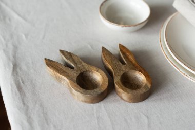 Paskalya ahşap yumurta bardakları masadaki tarafsız pamuk masa örtüsü üzerinde. Minimalist tarzda masa ayarları ve sıcak renkler