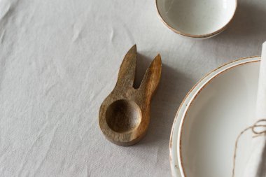 Paskalya ahşap yumurta bardakları masadaki tarafsız pamuk masa örtüsü üzerinde. Minimalist tarzda masa ayarları ve sıcak renkler