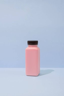 Mavi arka planda plastik bir şişe taze vejetaryen smoothie. Sağlık ve sağlıklı beslenme konsepti. Yaratıcı yiyecek ve içecek fotoğrafçılığı, kopyalama alanı