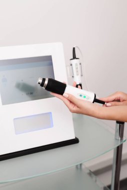 Kadının elinde gelişmiş teknolojilerin, Tripollar RF 'nin, Oxygeneo' nun ve Ultrasound 'un eşsiz bir kombinasyonu olan bir yüz gençleştirme cihazı var. Genç, taze ve doğal bir ten elde etmek için mükemmel bir yüz aygıtı.