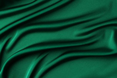 Soyut koyu zümrüt yeşil arka plan. Yumuşak dalgalı kıvrımlı yeşil ipek kumaş. Metin için alanı olan zarif bir arkaplan. Noel ya da Yeni Yıl masası