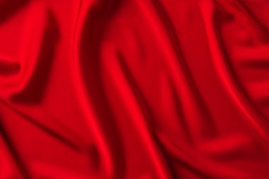 Kırmızı ipek kumaş arka plan. Yumuşak dalgalı kıvrımlı koyu kırmızı saten kumaş. Metin için alanı olan zarif arkaplan