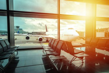 Havaalanı kapısı bekleme alanı ve jumbo jet günbatımı manzarası, seyahat konsepti