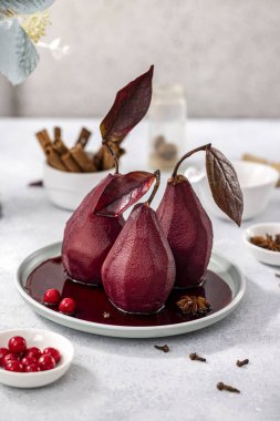 Pears in wine. Traditional french dessert pears stewed in red wine in plate on light surface. Concept for romantic dinner dessert.