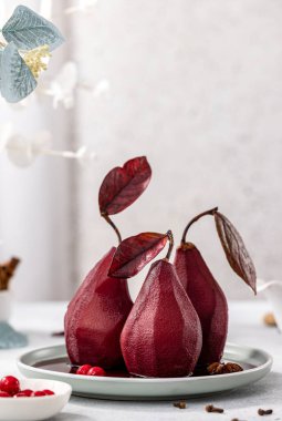 Pears in wine. Traditional french dessert pears stewed in red wine in plate on light surface. Concept for romantic dinner dessert.