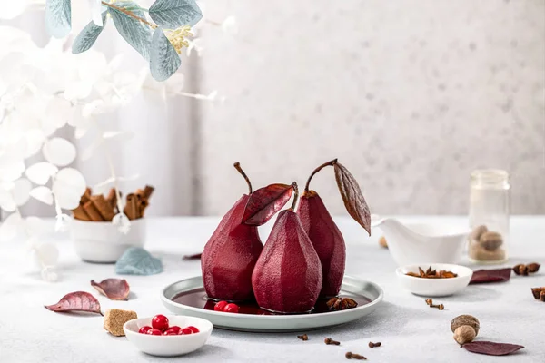 Pears in wine. Traditional french dessert pears stewed in red wine in plate on light surface. Concept for romantic dinner dessert.