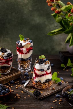 Yunan yoğurdu, böğürtlen reçeli, taze böğürtlen ve bardakta yabanmersini ile ev yapımı granola. Sağlıklı yemek, sağlıklı beslenme konsepti.