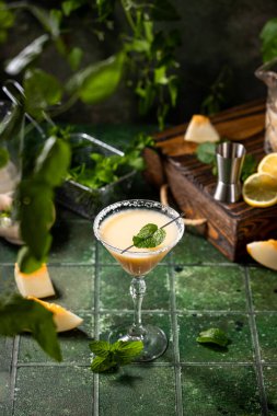 Koyu yeşil seramik zemin üzerinde nane şekerli kavun margarita kokteyli, yakın plan. Yaz sonbahar içkileri ve alkollü kokteyller. Alkolik kokteyl ya da detoks içeceği