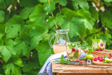 Ahududu ve limonata, dışarıdaki ahşap bir masada bir bardağa dökülüyor.