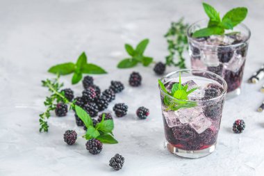 Buzlu, naneli ve kekikli iki bardak ferahlatıcı böğürtlen kokteyli.